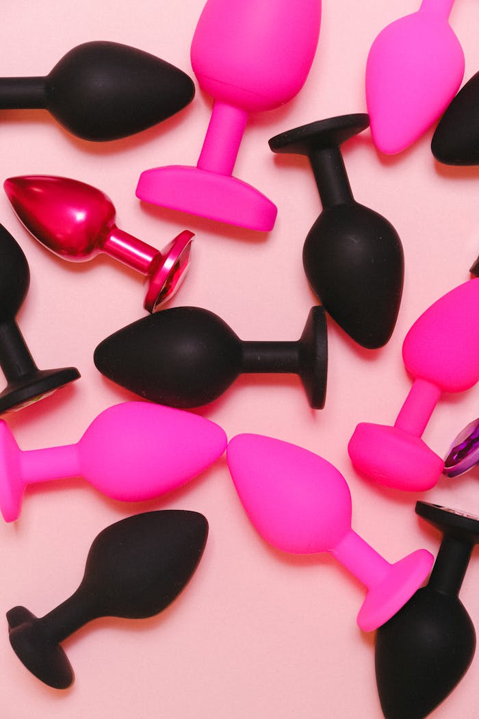 services-04 Bright and colorful collection of silicone adult toys on a pastel pink background.