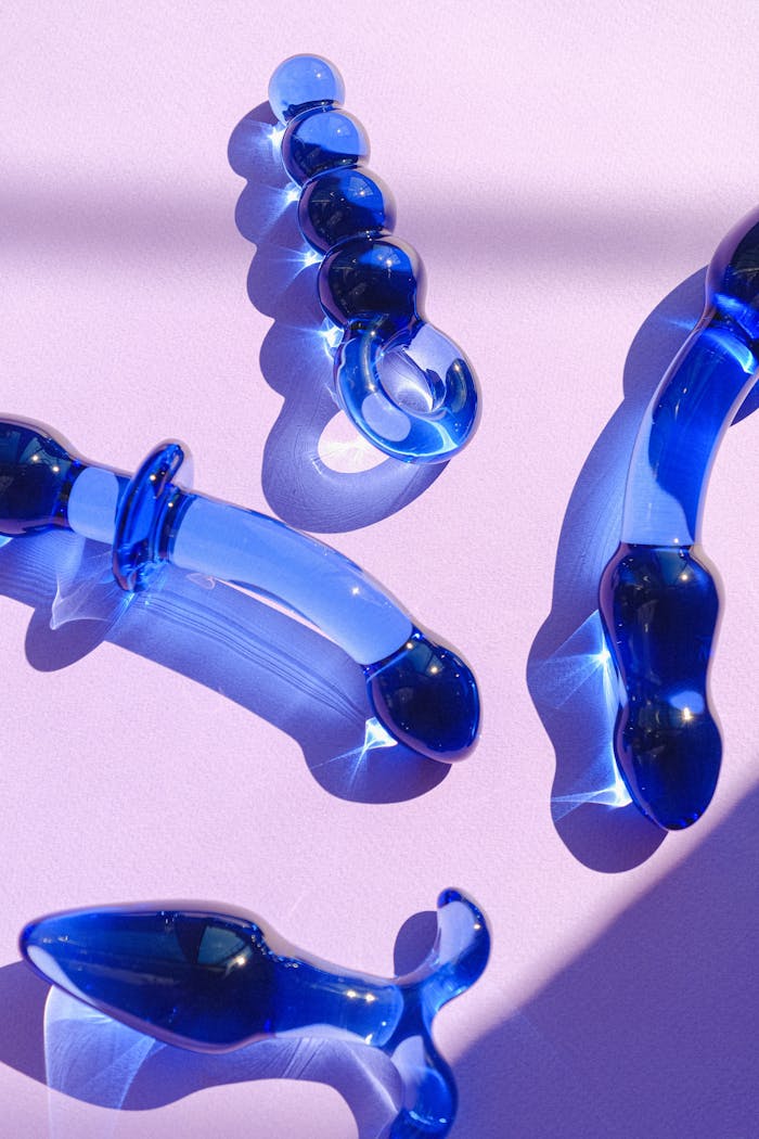 services-03 Stylish blue glass adult toys beautifully arranged on a pastel pink surface.